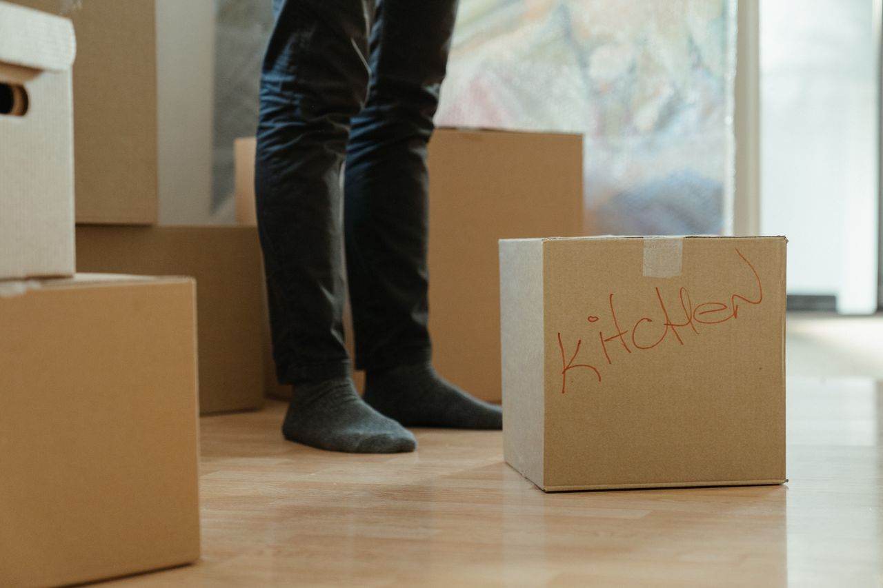 Services A person standing in a room surrounded by moving boxes labeled for the kitchen.